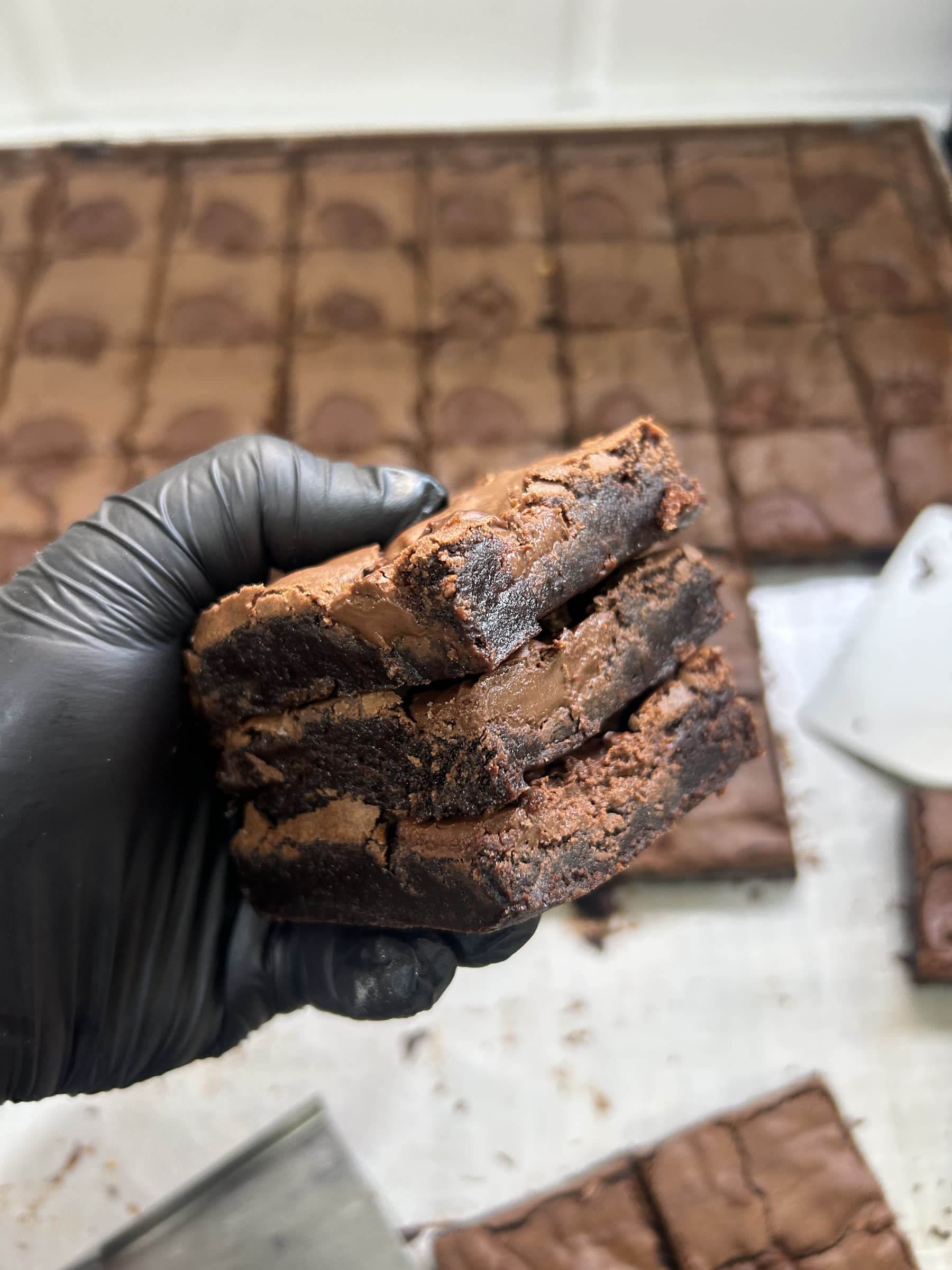 Mão segurando fatias de brownie recém-cortadas na produção da Iuzaks