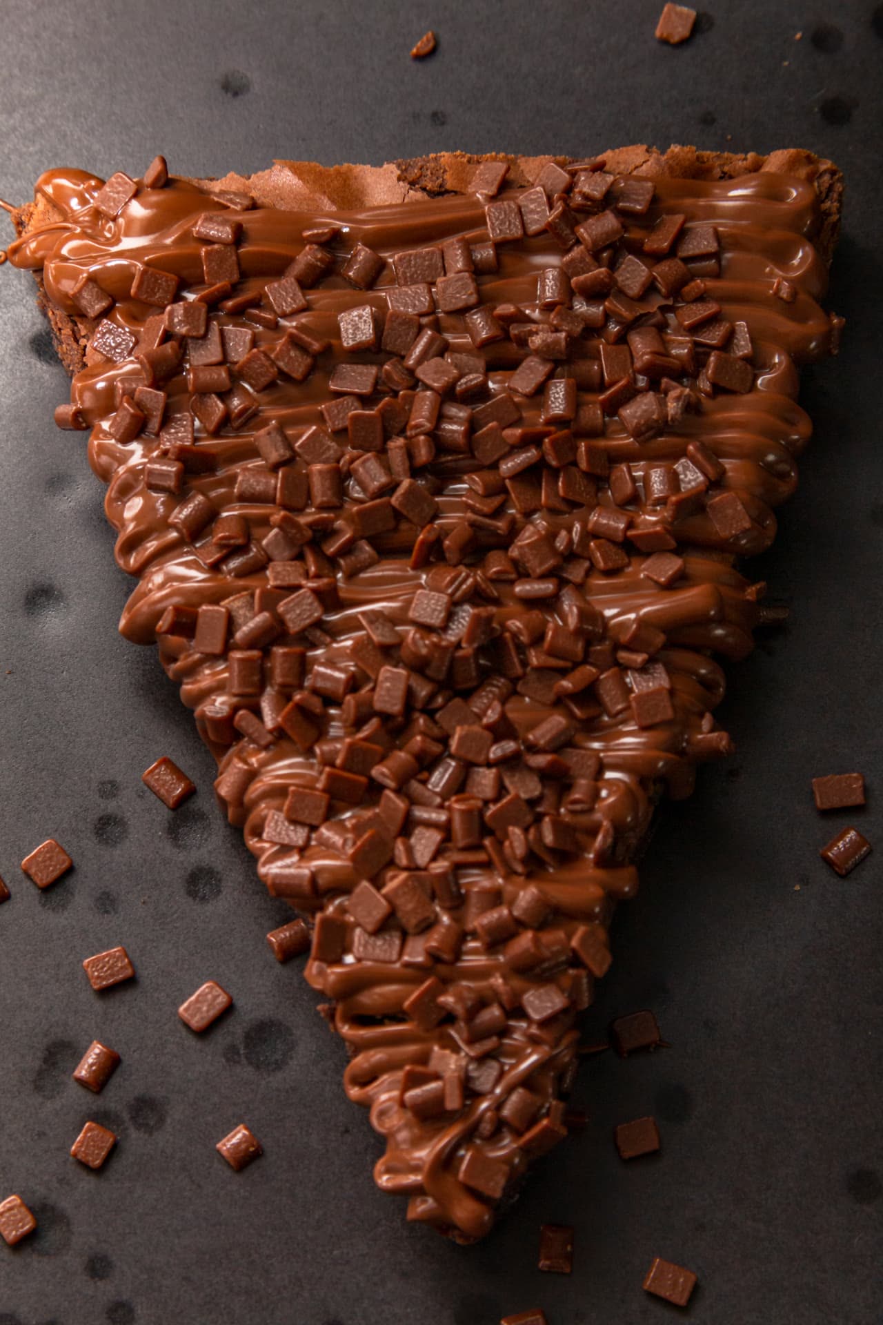 Fatia de brownie coberta com doce de leite e granulado belga